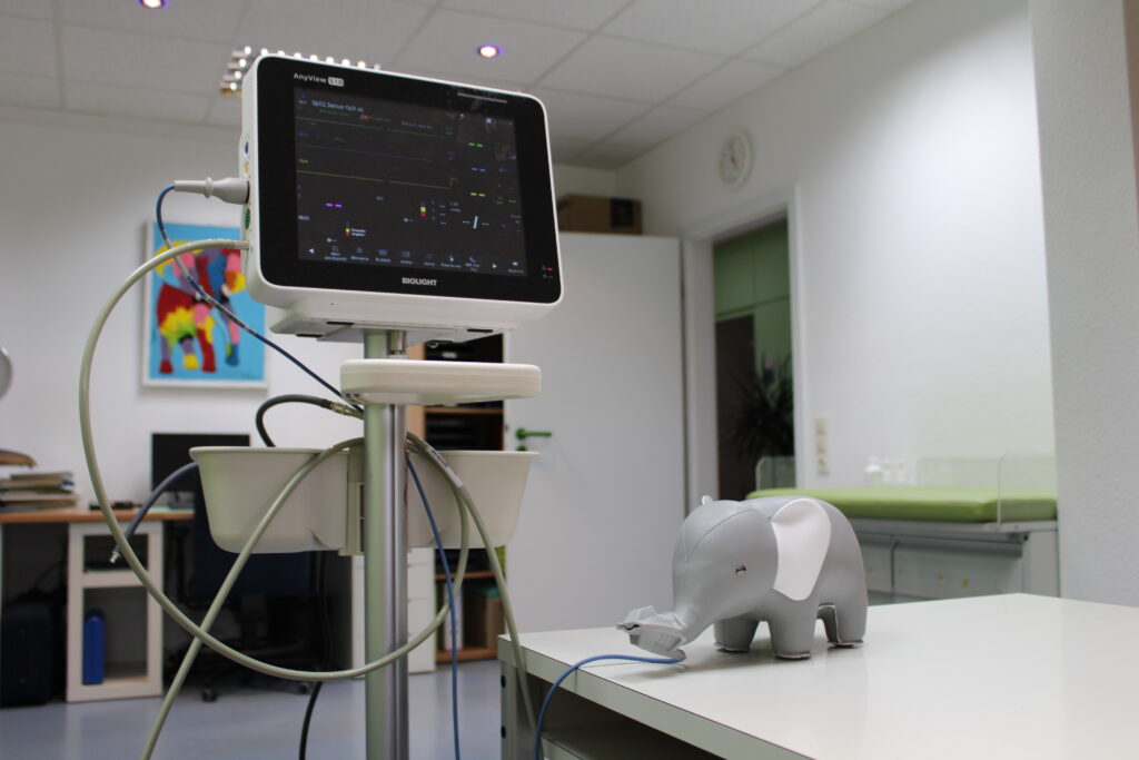 Das Praxismaskottchen lässt sich mit einem Pulsoxymeter am Rüssel untersuchen.